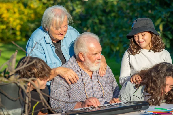 爷爷用乐器和孙子孙女在户外玩耍 — 图库照片