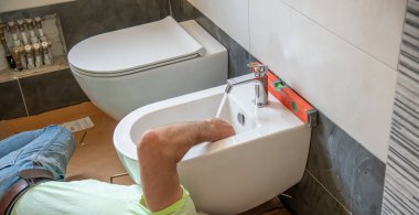 Tesisatçı yeni bir banyoya tuvalet kuruyor. Yeni bir ev konseptine geçiyoruz..