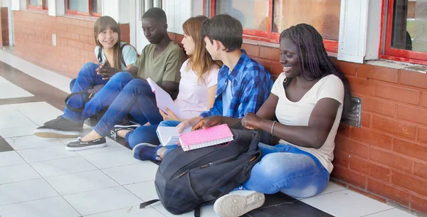 Diversity Students Friends Happiness Concept. Five schoolmates seated in the school hallway.