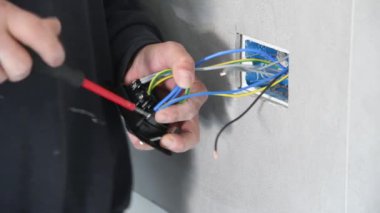 Elektrikçi konut elektrik sisteminin şalterleri ve prizleri üzerinde çalışıyor.