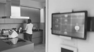 Akıllı ev kavramı. Tablet, modern bir evin içindeki akıllı ev simgelerini ve mutfakta çalışan kadınları gösteriyor..