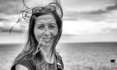 Denizin önünde gülümseyen mutlu kadın..