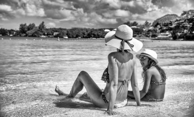 Back view of a beautful woman talking to her daughter on the shoreline. Holiday concept