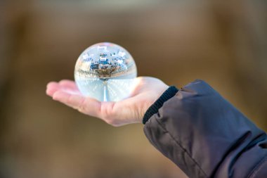 Kadının elinde modern bina içi ve salon yansıması olan Kristal Top var..