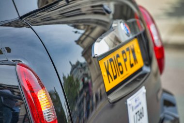 Londra, İngiltere - Haziran 2015: Siyah taksi plakası ve şehir yansımaları.