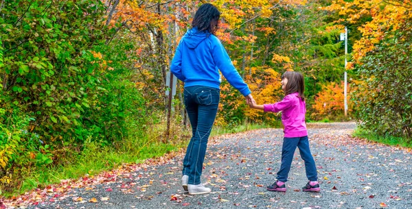 Woman walking along a trail with her daughter in fall season.