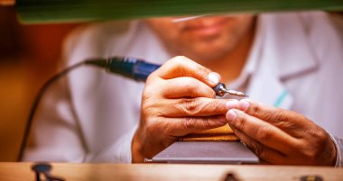 Clockmaker repairing wrist watch in a workshop.