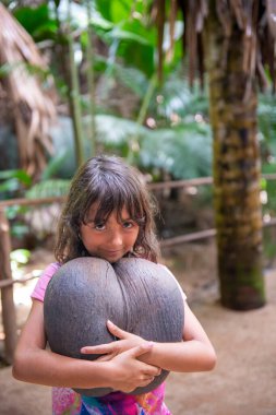 Young girl embracing Coco De Mer along a beautiful tropical trail, Vallee de Mai.