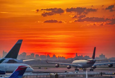 Backlit view of airplanes on the airport runway at sunset. Travel around the world concept.