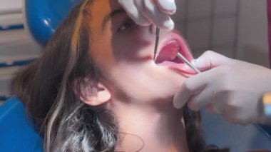Diş hekiminin eli hastaya elastik lastik bant takıyor. Diş tellerinde metal diş teli olan kız ortodontik tedavi görüyor..