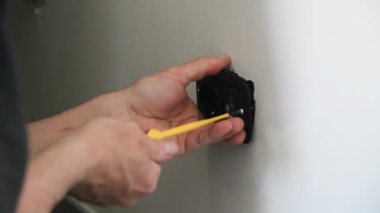 Elektrikçi konut elektrik sisteminin şalterleri ve prizleri üzerinde çalışıyor.