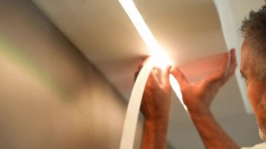 Installation of LED strip, glowing ribbon close-up. Man at work.