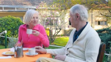 Active seniors having breakfast in the garden.