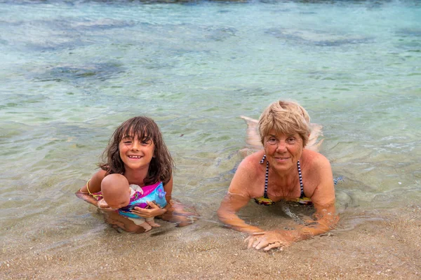 Young girl with her grand mother on the shoreline of Seychelles, holiday and travel concept.