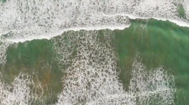 Beautiful waves along the shoreline, overhead aerial view from drone.