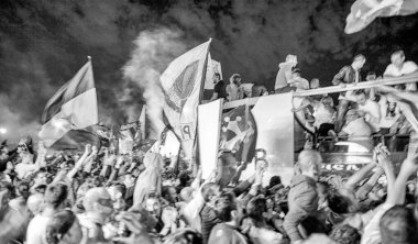 PISA, ITALY - JUNE 15TH, 2016: Local fans celebrate the soccer team's promotion. Celebrations in the night with smoke bombs and an open bus.