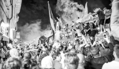 PISA, ITALY - JUNE 15TH, 2016: Local fans celebrate the soccer team's promotion. Celebrations in the night with smoke bombs and an open bus.