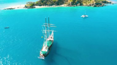 Overhead aerial view of a sailing ship arriving at island destination.
