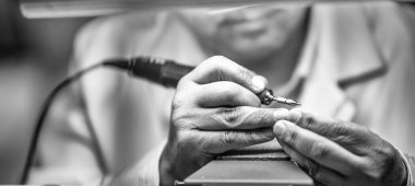 Clockmaker repairing wrist watch in a workshop.