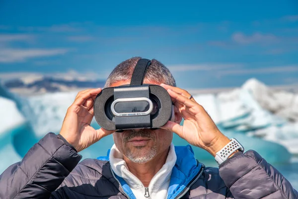 A man with a virtual reality visor explores the beautiful Jokulsarlon Beach full of icebergs.