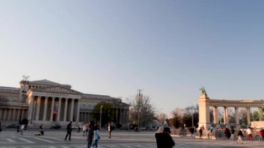 BUDAPEST, HUNGARY - Nisan 2019: Turistler gün batımında Kahramanlar Meydanı 'nı ziyaret ediyor. Şehir yılda 3 milyon kişiyi çekiyor.