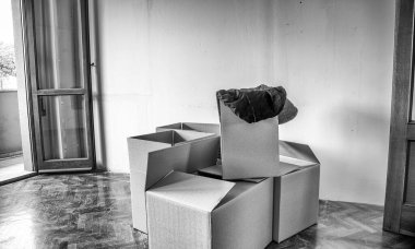 Yeni bir ev kavramına geçiyorum. Boş bir odanın parke zemininde karton kutular var.