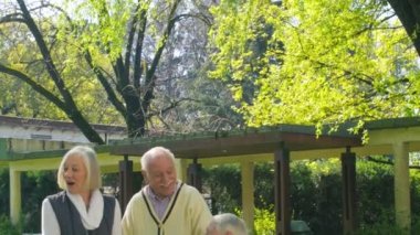 Active seniors. Two elderly couples speaking to a young lady in the garden.