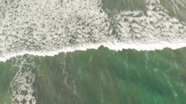 Beautiful waves along the shoreline, overhead aerial view from drone.
