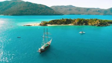 Sailing ship near the shoreline of a beautiful tropical island, aerial view.