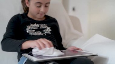 Tablet ekranı temizleyen kadın. Coronavirus önleme tedbirleri.