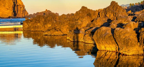日没時の岩の反射 背景の天然溶岩プールと海 — ストック写真