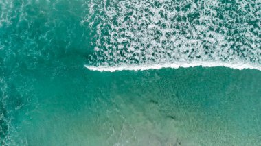 Above the ocean, aerial view at the waves and surface near shoreline - Drone viewpoint.