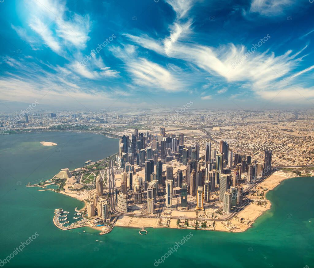 Aerial view of Doha skyline from airplane. Modern skyscrapers at sunset, Qatar.