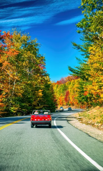 旧时的红色轿车在落叶季节沿着新英格兰的一条道路行驶 — 图库照片