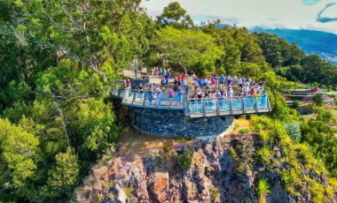 Tourists enjoy the viewpoint at Cabo Girao, along the Madeira coastline, Portugal. Aerial view from drone.