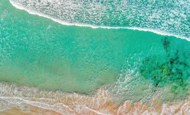 Above the ocean, aerial view at the waves and surface near shoreline - Drone viewpoint.