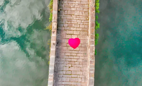 Aerial overhead view of Devils Bridge, Lucca. Red heart shape umbrella on the bridge.