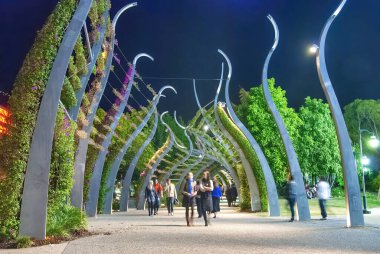 Avustralya 'nın Brisbane kentinde geceleyin South Bank Grand Arbour boyunca turistler. 1 km uzunluğunda bir arbour, bukleli kuleler çiçek açmış begonvillerle örtülmüş..