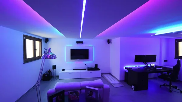 Smart home system monitor screen with all the lights on with different colors. Sofa and modern Tv.