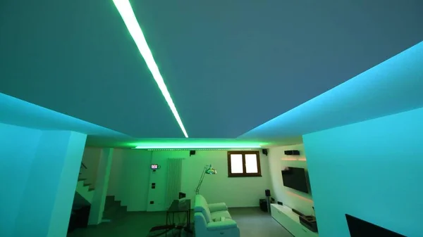 Led strips lighting in a modern living room with sofa, desk and TV screen.