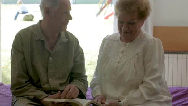 Slow Motion Caucasian Elderly Retired Couple Reading Book Seated Bed — Stock Video