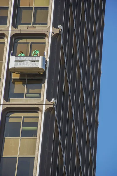 晴れた日に超高層ビルの窓を掃除する二人の労働者 — ストック写真