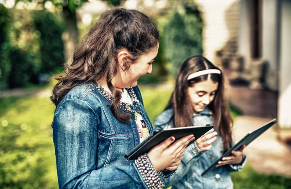 Två Unga Flickor Som Använder Tabletter Stående Stadsparken — Stockfoto