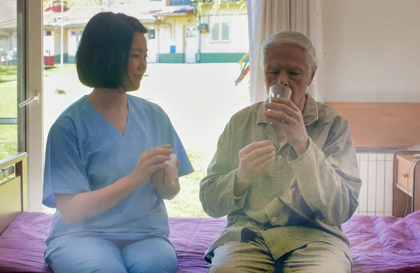 Genç Asyalı Kadın Doktor Yaşlı Bir Adamın Hastane Yatağında Ilaç — Stok fotoğraf