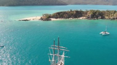 Overhead aerial view of a sailing ship arriving at island destination.