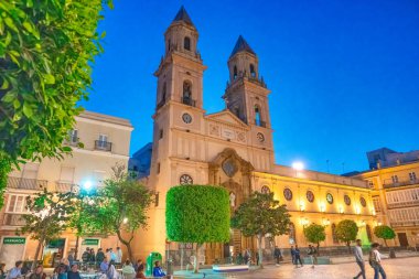 Cadiz, İspanya - 8 Nisan 2023: Günbatımında Iglesia de San Antonio boyunca turistler.