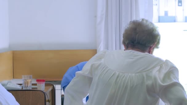 Uma Enfermeira Ajuda Uma Mulher Idosa Hospital Levantar Cama — Vídeo de Stock