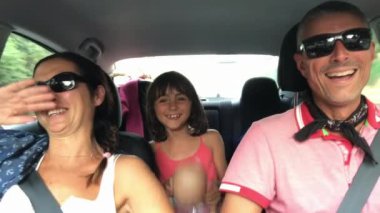 Neşeli, genç, geleneksel ailenin uzun bir araba yolculuğu var. Yaz Gezisi. Üç kişilik mutlu bir beyaz aile, araba sürüyor ve otomobille gezerken eğleniyorlar..
