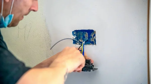 電気技師は壁にコンセントを取り付け ケーブルを接続します — ストック写真