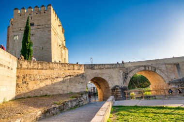 Cordoba, İspanya - 11 Nisan 2023: Turistler gün batımında Roma köprüsü boyunca yürürler.